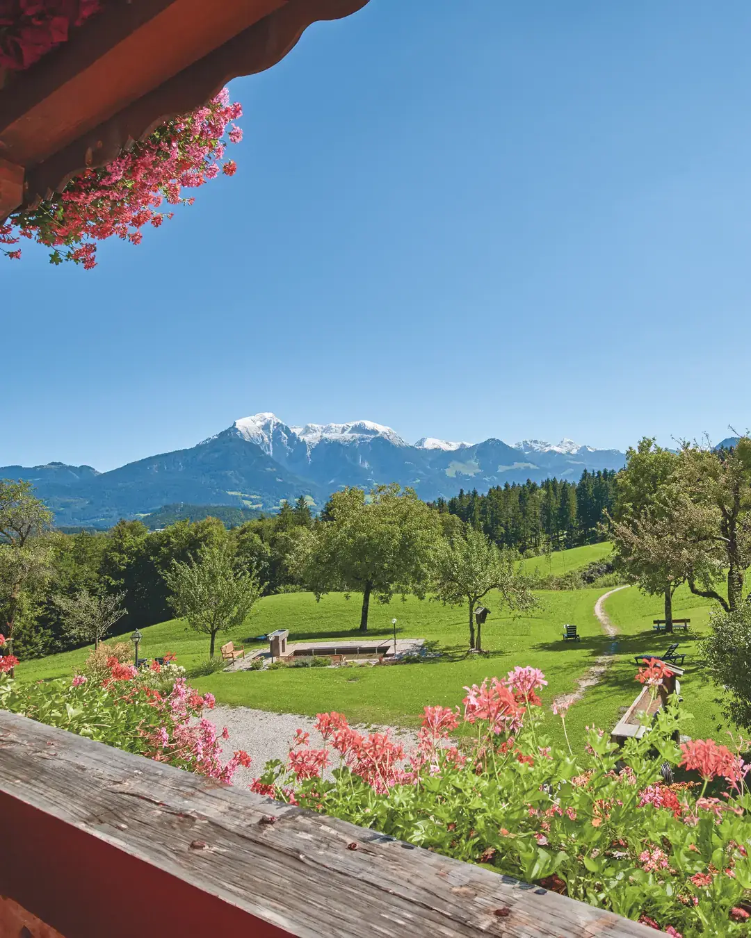 Blick vom Blumenbalkon des Alpenhotels Hundsreitlehen über die Bergwiese mit Kneippanlage zu den Berchtesgadener Alpen