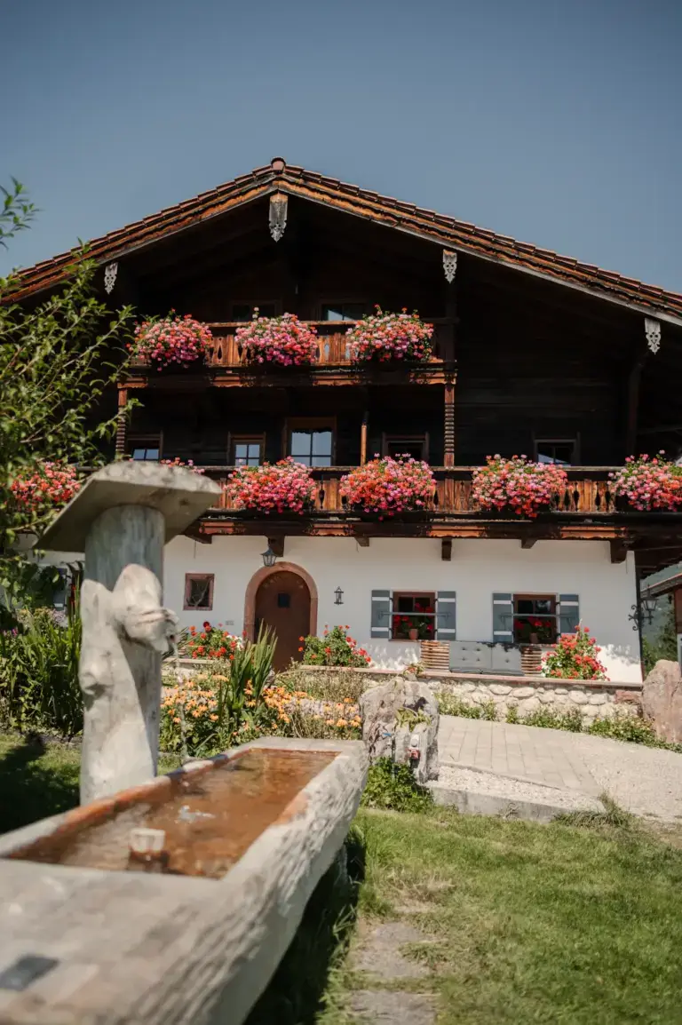 Fassade des Alpenhotels Hundsreitlehen mit Holzbrunnen und Blumenschmuck