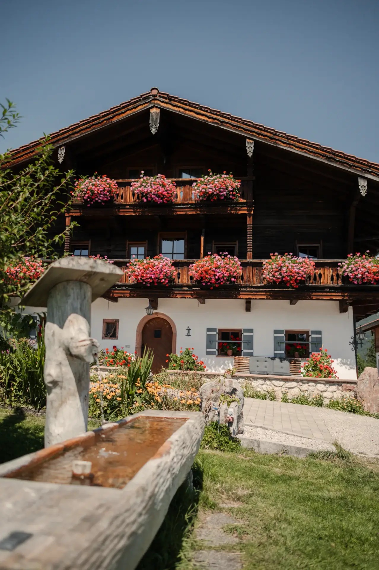 Fassade des Alpenhotels Hundsreitlehen mit Holzbrunnen und Blumenschmuck
