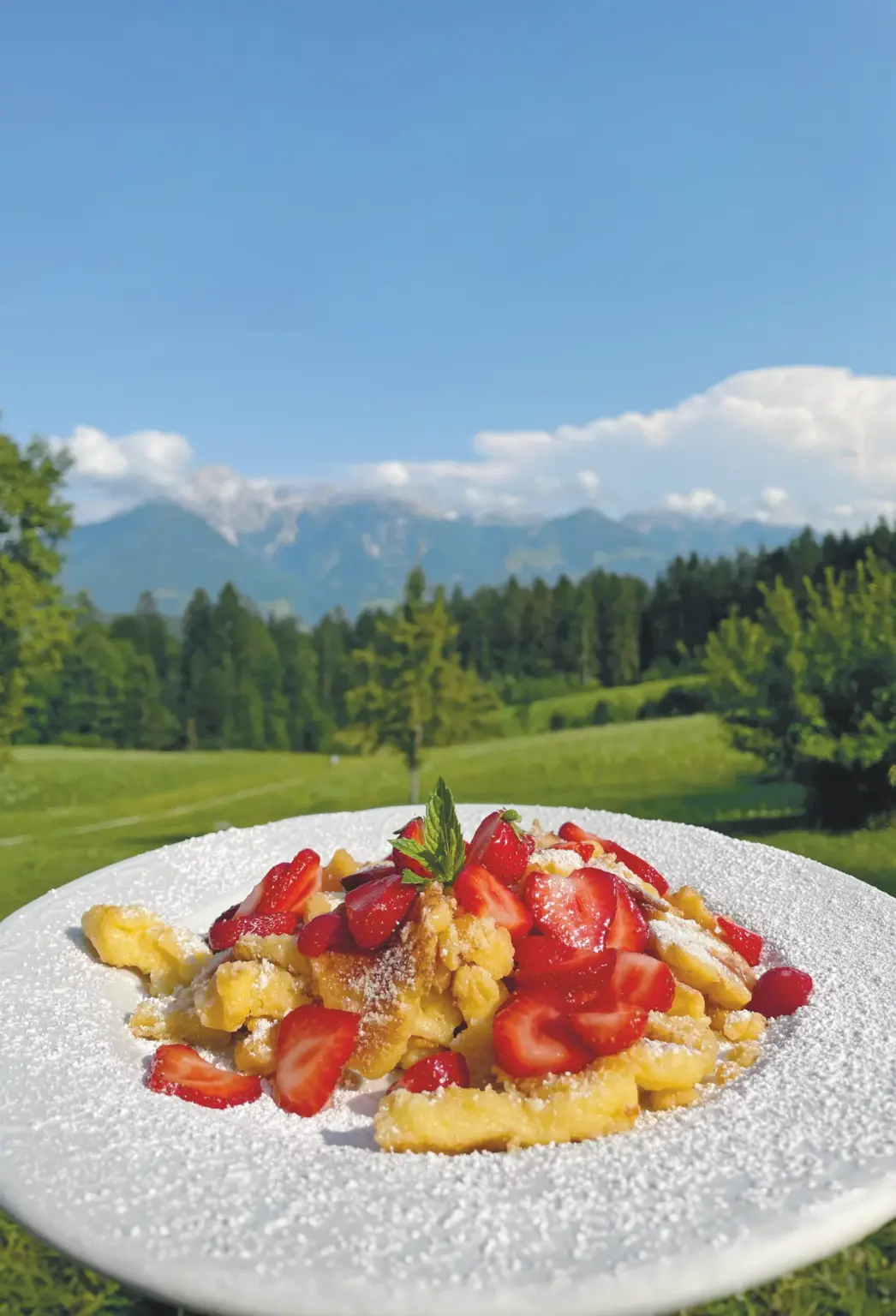 Kaiserschmarrn mit frischen Erdbeeren vor Bergkulisse