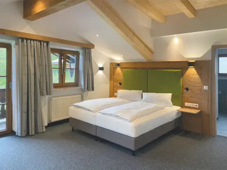Modernes Zimmer mit Holzelementen und Balkontür im Alpenhotel Hundsreitlehen