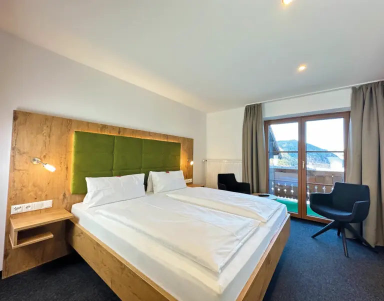 Helles Zimmer mit Doppelbett und Blick ins Grüne im Alpenhotel Hundsreitlehen