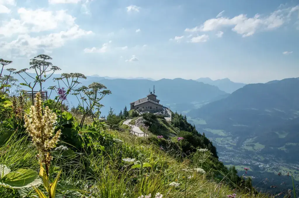 Kehlsteinhaus auf dem Gipfel des Kehlsteins mit Bergblumen im Vordergrund