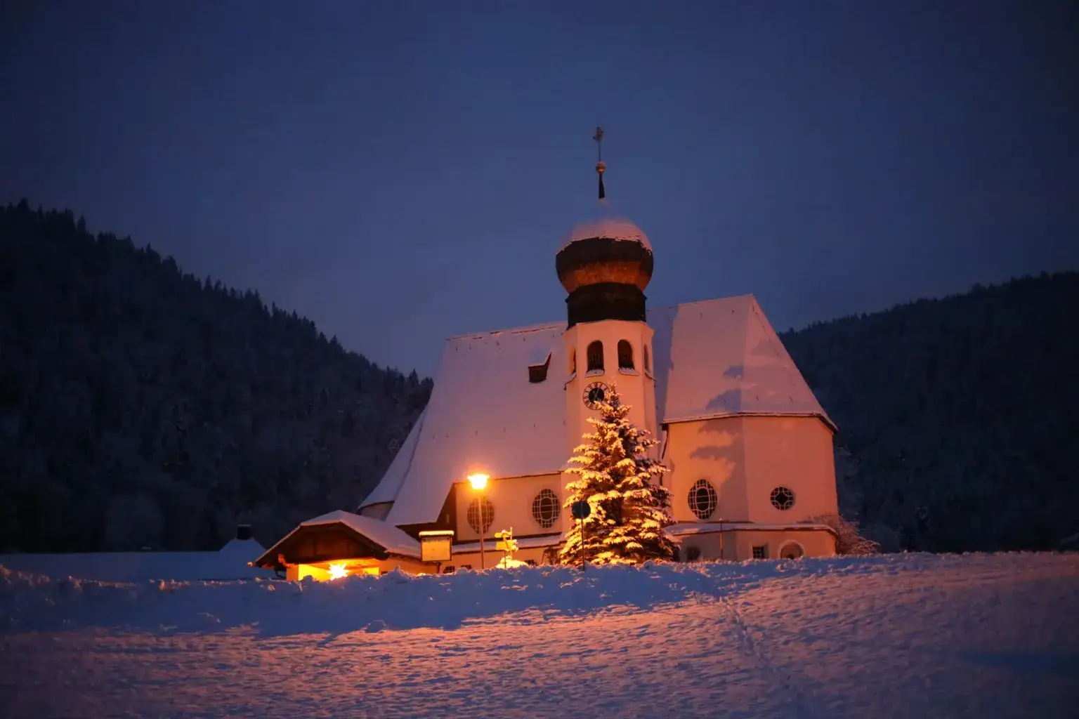 Kirche in Oberau mit Christbaum im Schnee zur Adventszeit