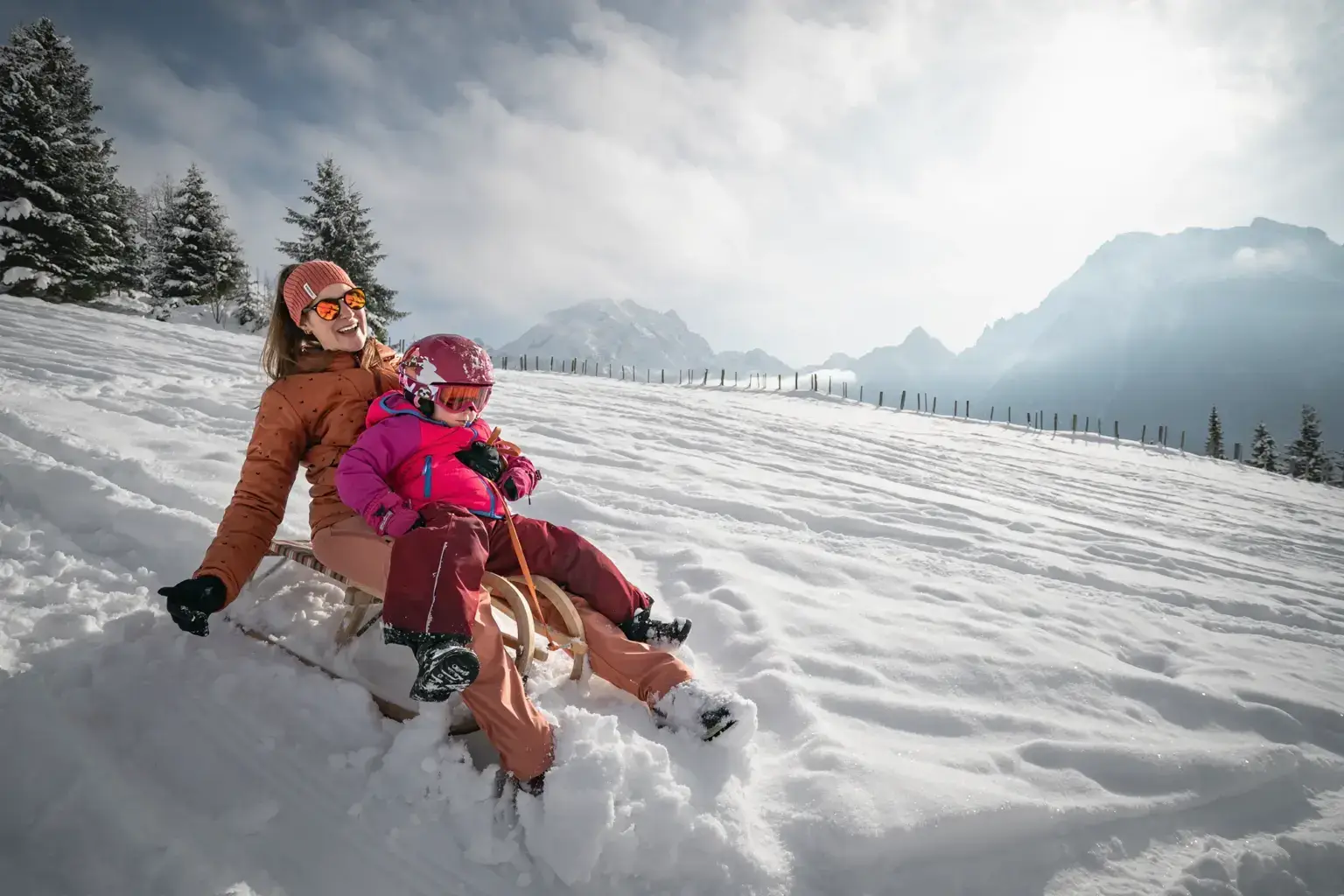 Mutter und Kind beim Rodeln im Schnee im Berchtesgadener Land