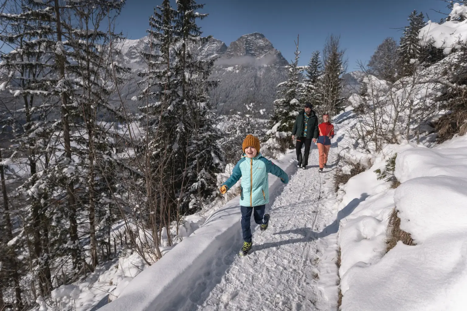 Familie beim Winterwandern auf verschneitem Weg im Berchtesgadener Land